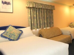 Habitación de hotel con dos camas, un ventanal con cortinas y un cuadro en la pared.
