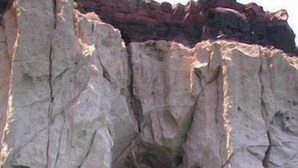 Eine natürliche Felsformation mit einem hohlen Bogen über ruhigem, türkisblauem Wasser.