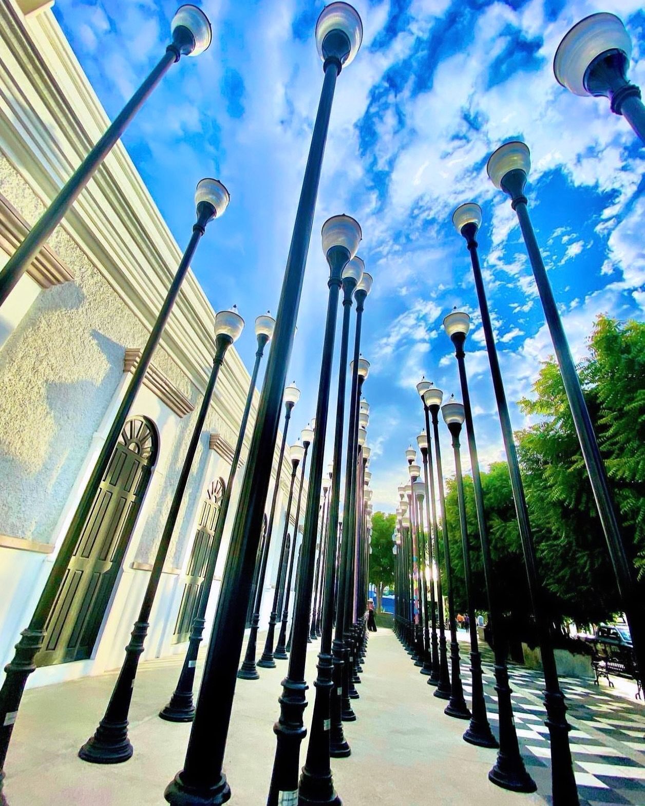 Una fila de farolas altas con un edificio al fondo.