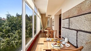 A balcony with a dining table set for breakfast, overlooking a forested area.