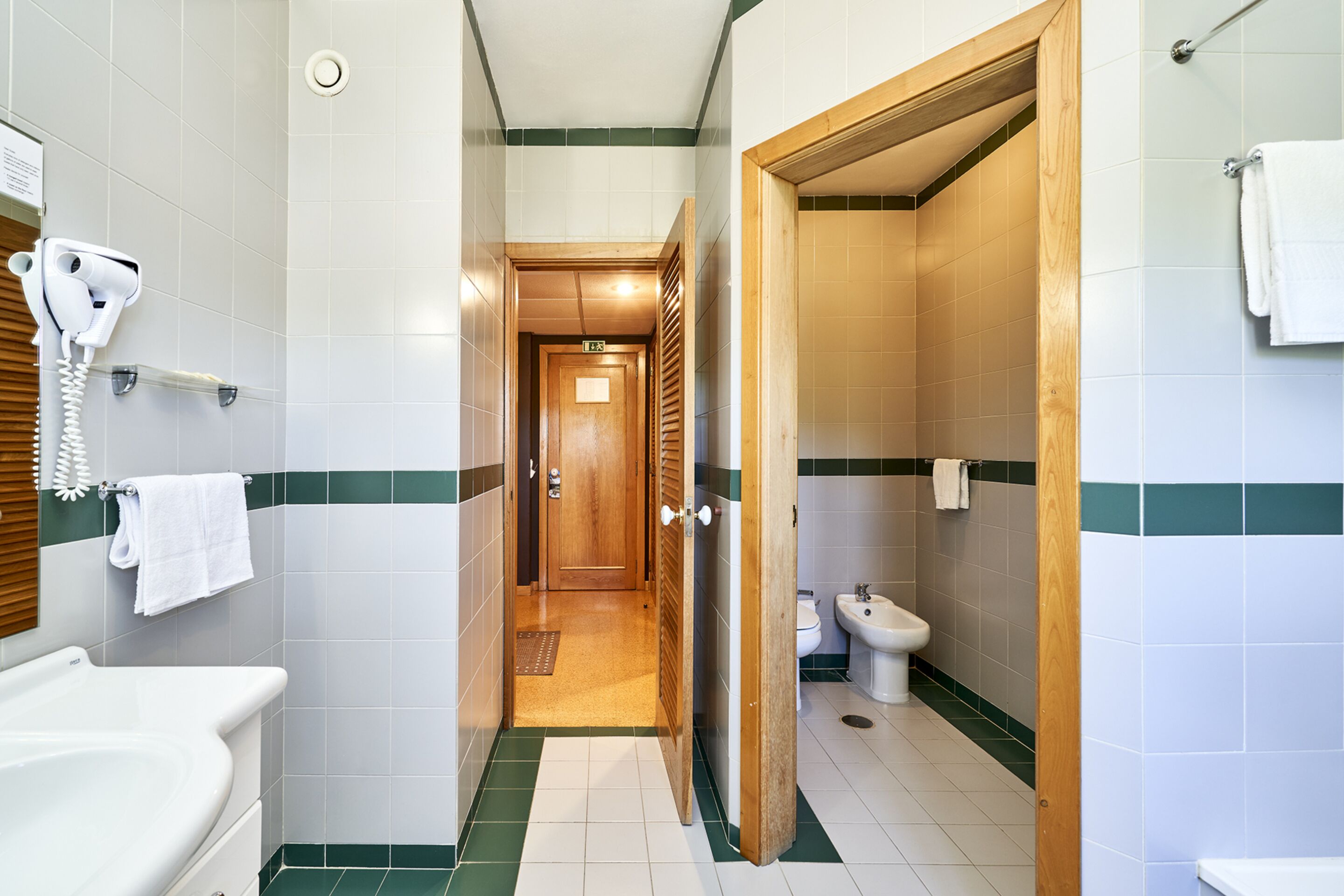 A hotel bathroom with a shower, toilet, and sink.