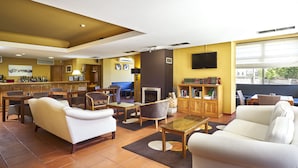 A hotel lobby with a bar area, seating arrangements, a fireplace, and a bookshelf.