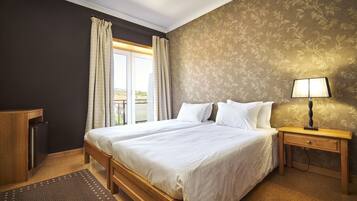 A neatly arranged bedroom with a large bed, a bedside table with a lamp, a wardrobe, and a window with curtains.
