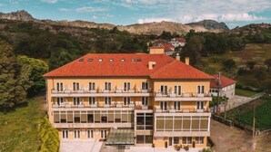 A multi-story hotel with a red-tiled roof, balconies, and a view of the surrounding landscape.