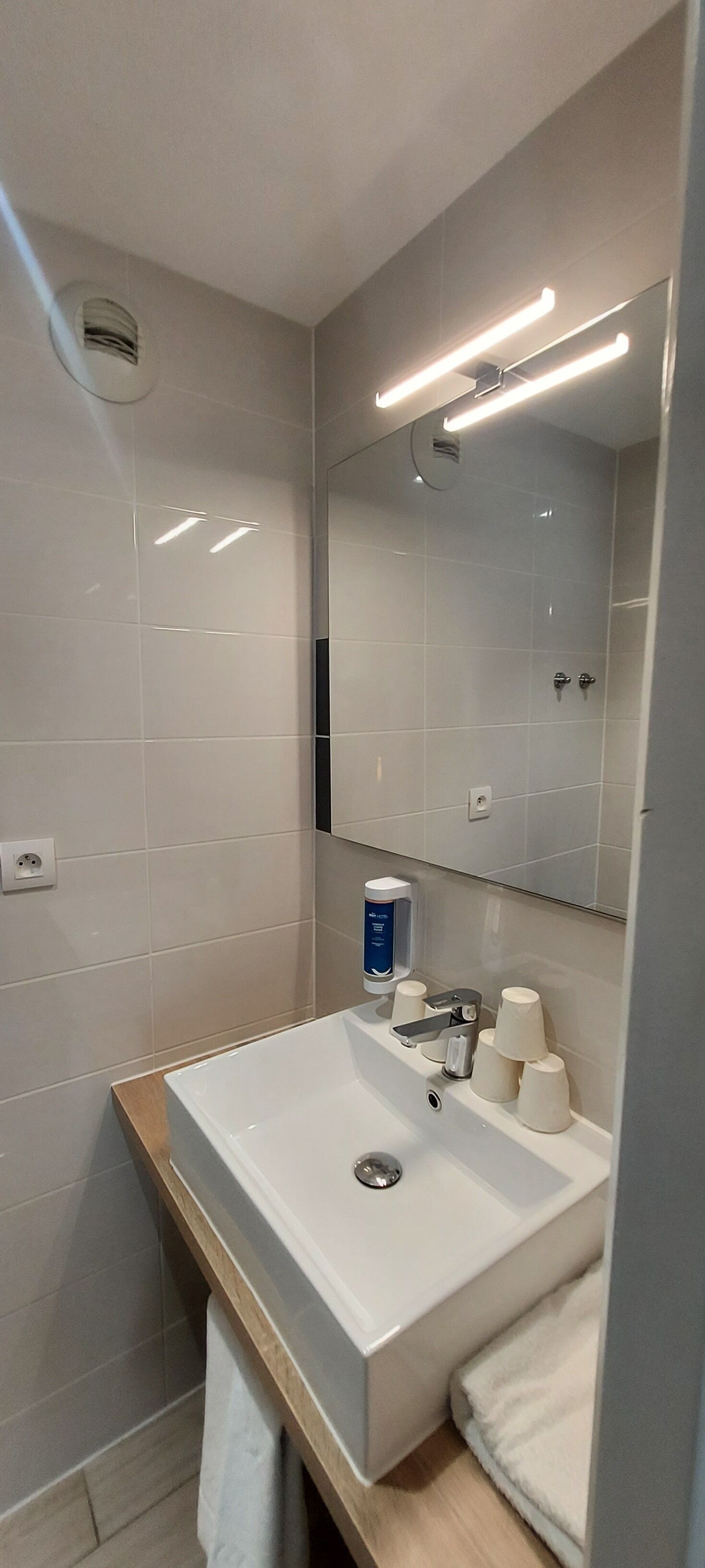 Une salle de bain moderne avec un lavabo blanc, un miroir et un porte-serviettes.