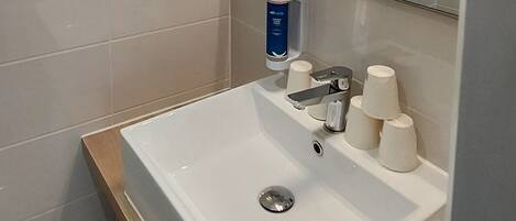 Une salle de bain moderne avec un lavabo blanc, un miroir et un porte-serviettes.