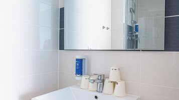A modern bathroom with a large mirror, a white sink, and a towel on the counter.