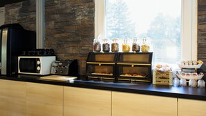 A kitchen counter with a coffee machine, toaster, and various food items. - Brit Hotel Confort Manosque Cadarache (Manosque)