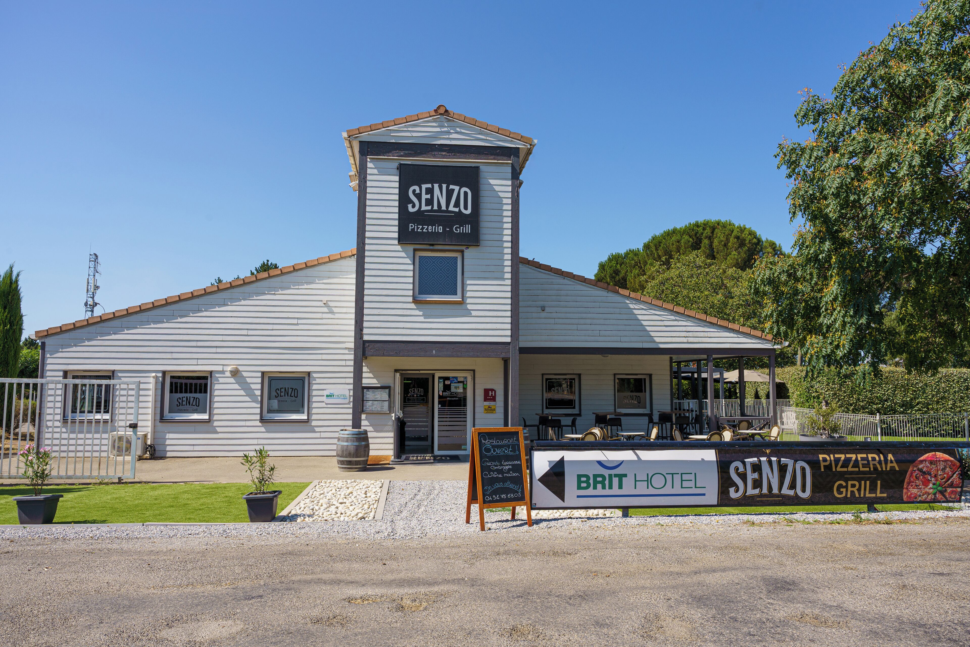 Rakennuksen edessä on kyltti, jossa lukee: ”SENZO Pizzeria – Grill” ja toinen kyltti, jossa lukee: ”BRIT HOTEL”.