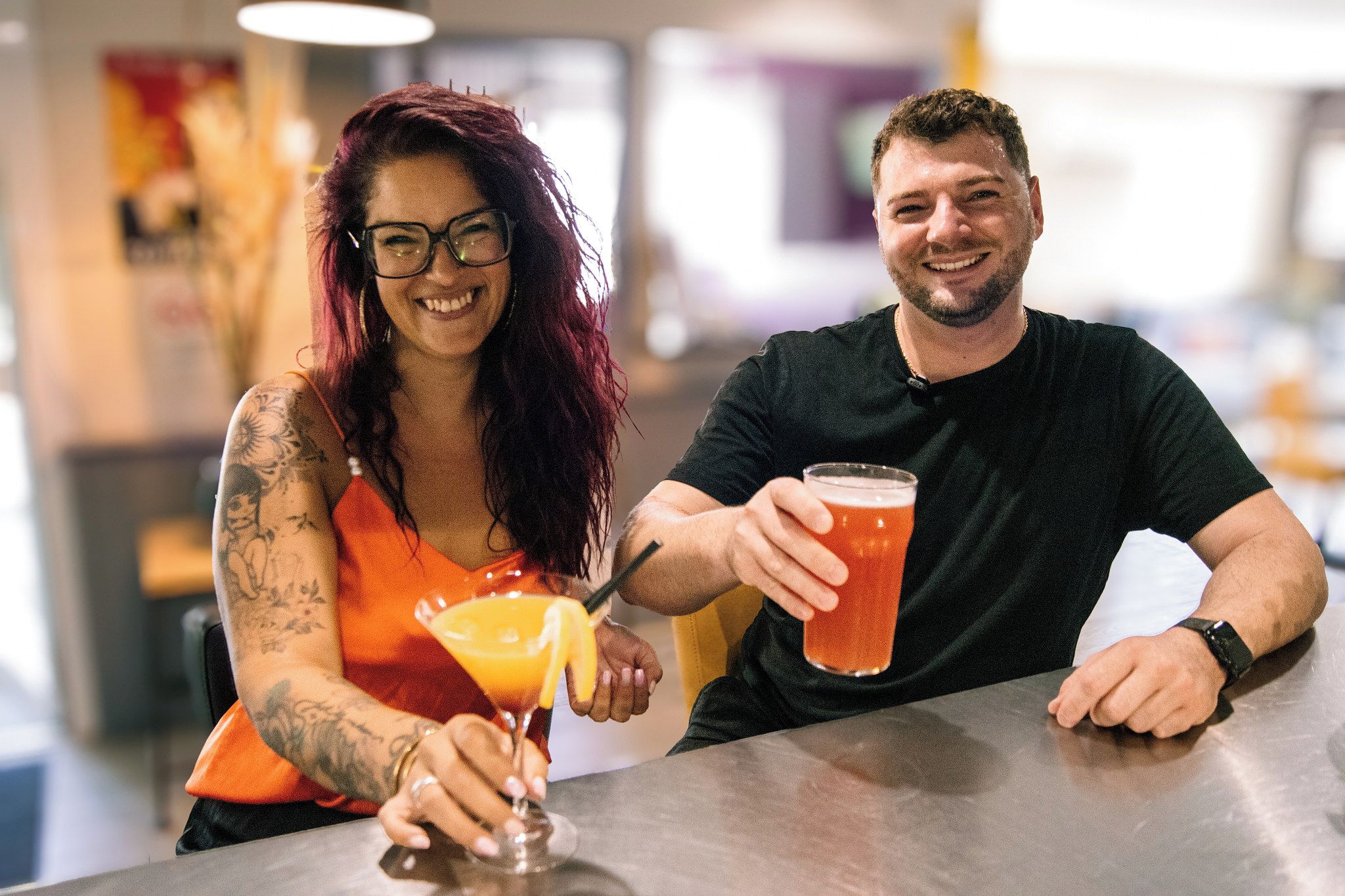 Two people sitting at a bar with drinks.