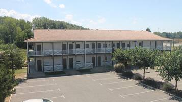 A two-story motel with a tiled roof, multiple balconies, and a parking lot.