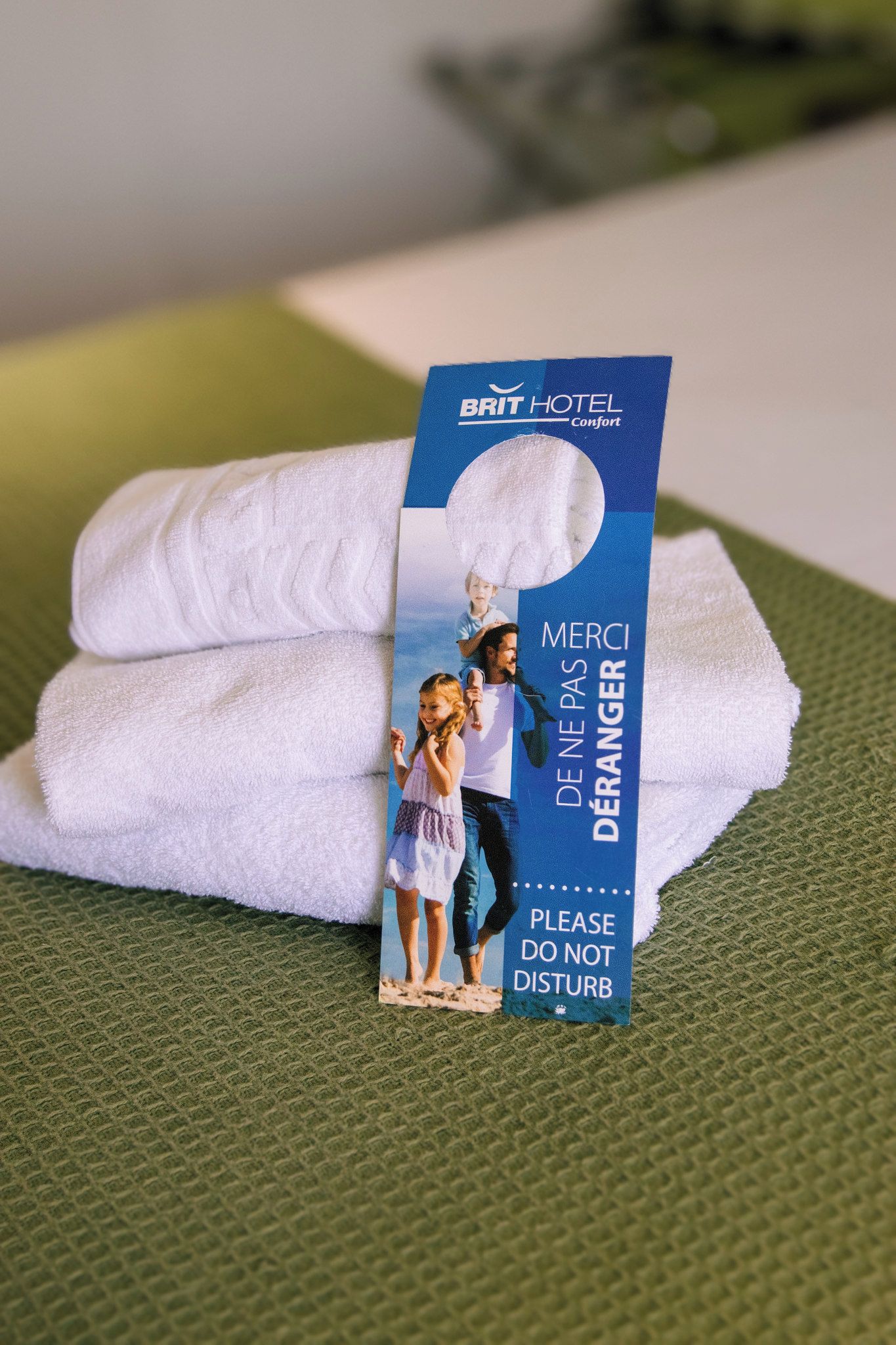 Een BRIT HOTEL handdoek met een bordje 'Merci De Ne Pas Disturb'.