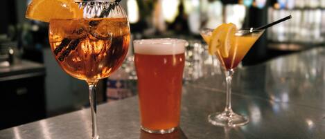 Three glasses of beverages on a bar counter.