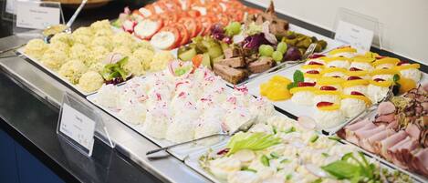 Un bufé con diversas opciones de comida, como ensaladas, frutas y carnes.