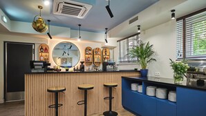 A modern bar area with a wooden counter, three stools, and a mirror. There are shelves with bottles and a coffee machine. - Hotel Halo Toruń (Torun)