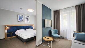 A hotel room with a bed, a desk, a chair, and a sofa. - Hotel Halo Toruń (Torun)