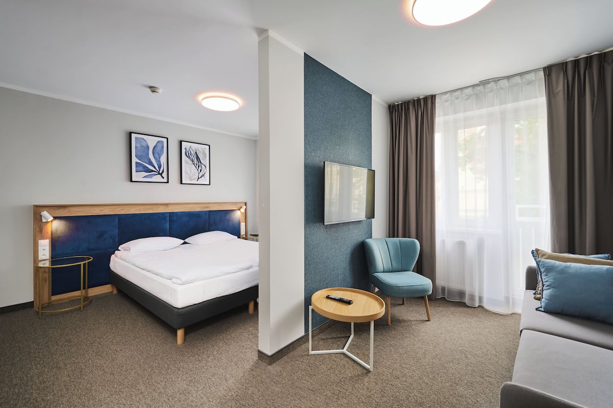 Ein Hotelzimmer mit Bett, Schreibtisch, Stuhl und einer Couch.