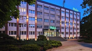 A multi-story hotel with a prominent 'Halo' sign, featuring a modern architectural design with brick accents and a well-lit entrance. - Hotel Halo Toruń (Torun)