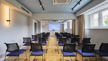 A conference room with rows of chairs, a projector screen displaying "Halo," and a podium.