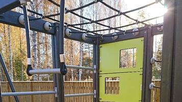 Children can play safely within the enclosed playground area, featuring a climbing net and metal bars.