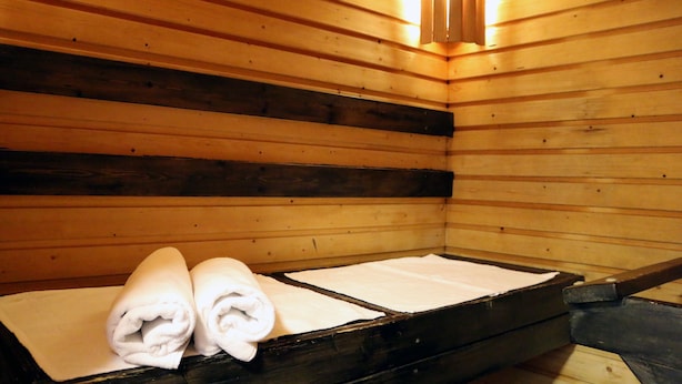 A wooden sauna room with benches and towels. - Hotel Oravi - Apartments (Savonlinna)
