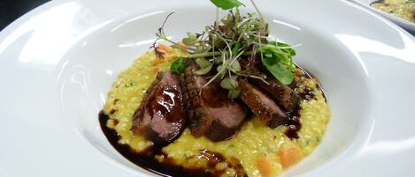 A white plate with a dish of meat and vegetables, garnished with greens.