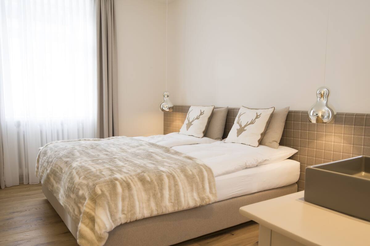 A neatly arranged hotel room with a bed, a bedside table, and a window with curtains.