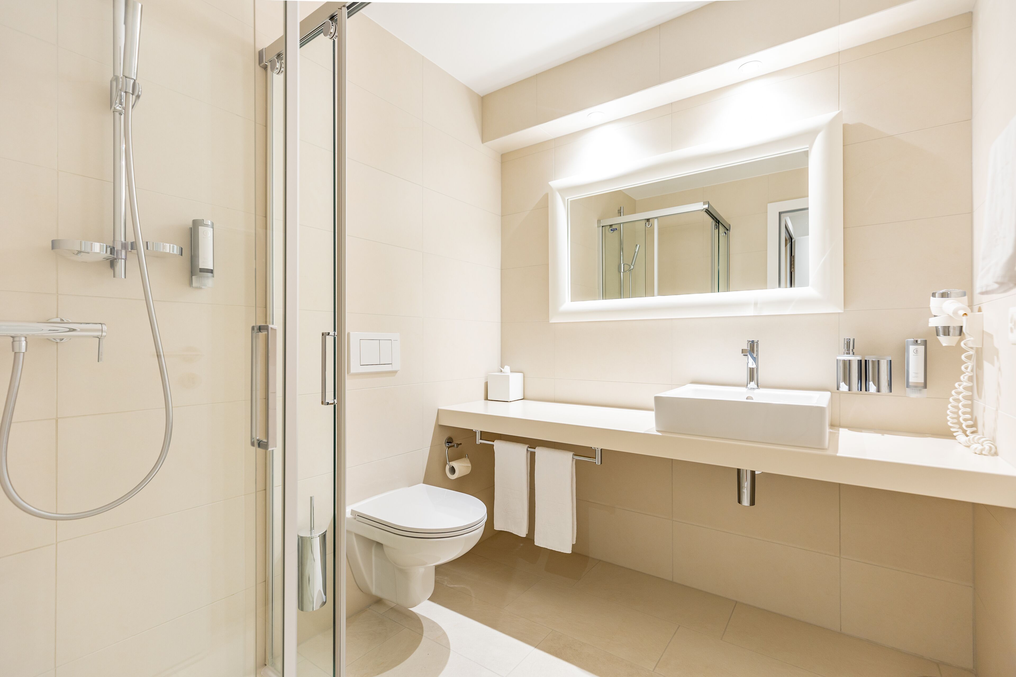 A modern bathroom with a glass-enclosed shower, a toilet, a sink, and a mirror above the sink.