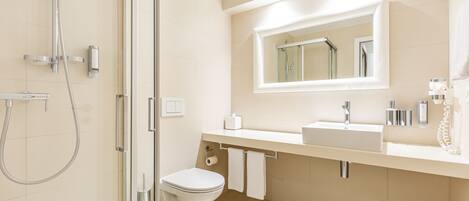 A modern bathroom with a glass-enclosed shower, a toilet, a sink, and a mirror above the sink.