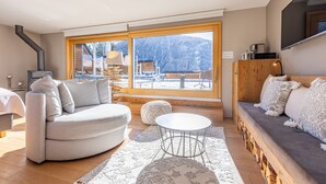 Un salon moderne avec une grande fenêtre, un canapé, une table basse et une cheminée.