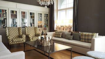 A living room with a sofa, armchairs, a coffee table, and a bookshelf filled with books.