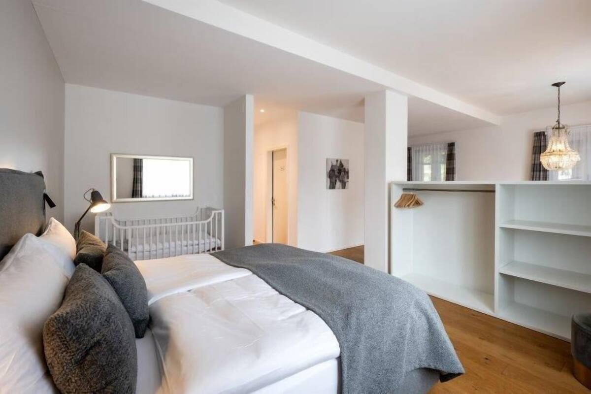 A modern bedroom with a bed, bedside lamp, and a wardrobe.