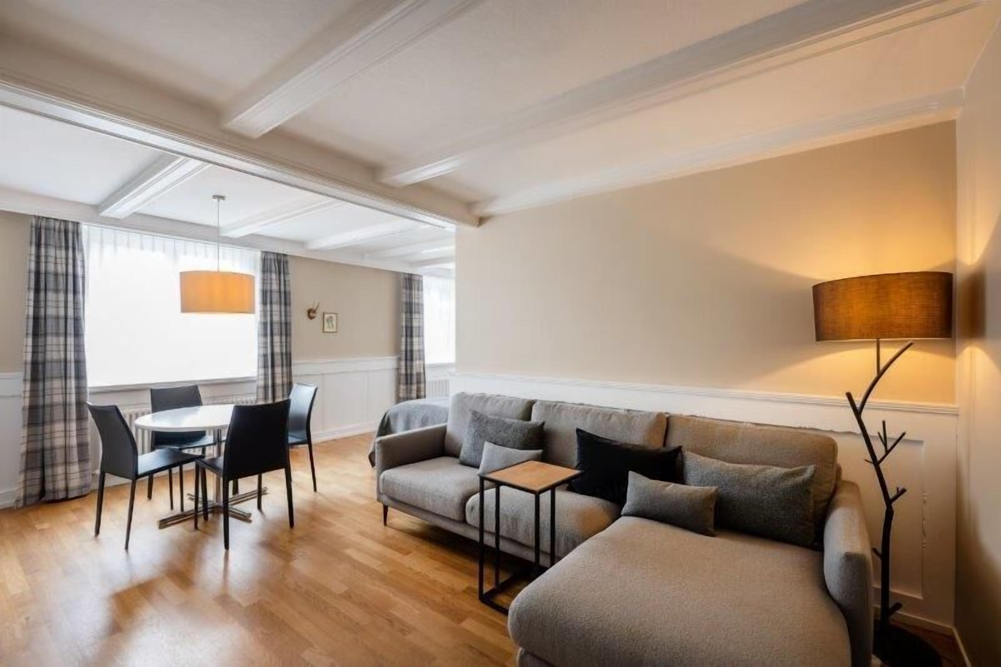 A modern living room with a sofa, a coffee table, and a dining area with chairs.