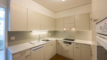 A modern kitchen with white cabinetry, a built-in dishwasher, and a stainless steel sink.