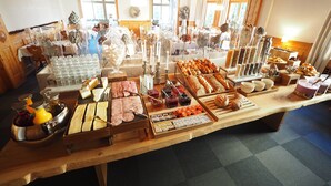 A buffet with various food items and beverages, wooden furniture, and a chandelier. - Hotel Edelweiss (Davos)