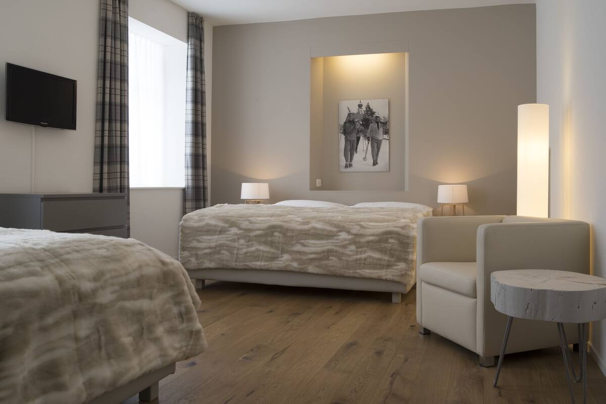 A hotel room with two beds, a TV, a painting, and a lamp.