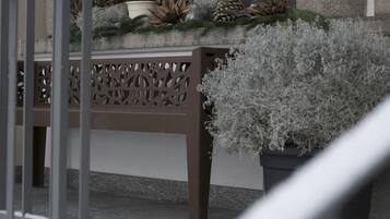 Una escalera con barandilla, un banco con un arreglo decorativo y una planta en maceta.
