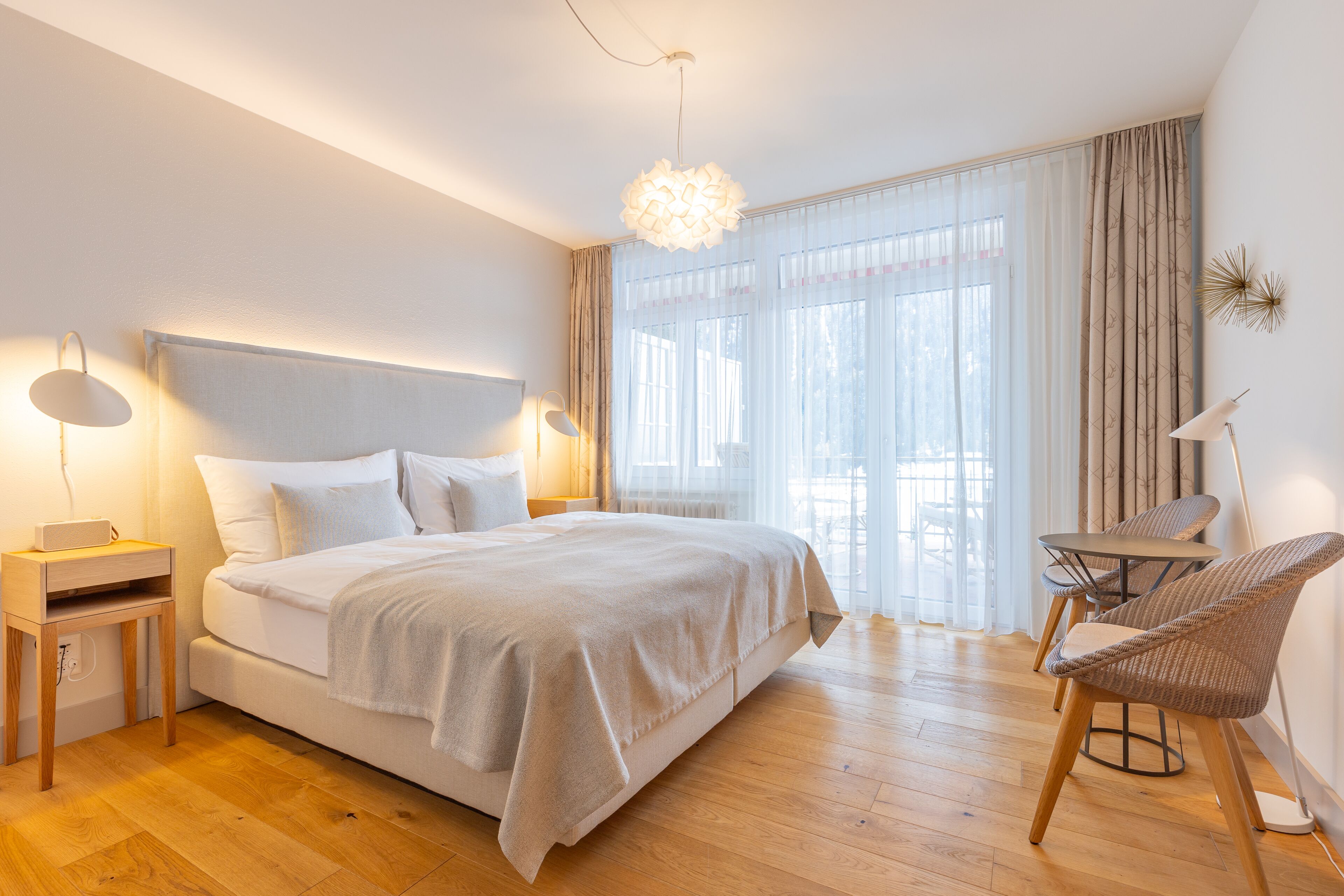 Un dormitorio moderno con una cama grande, mesitas de noche, un escritorio y una silla.