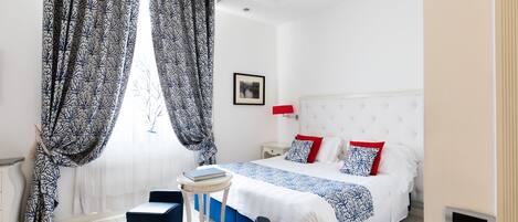 Ein modernes Hotelzimmer mit einem großen Bett, einem Nachttisch, einem kleinen runden Tisch und einem Sessel.