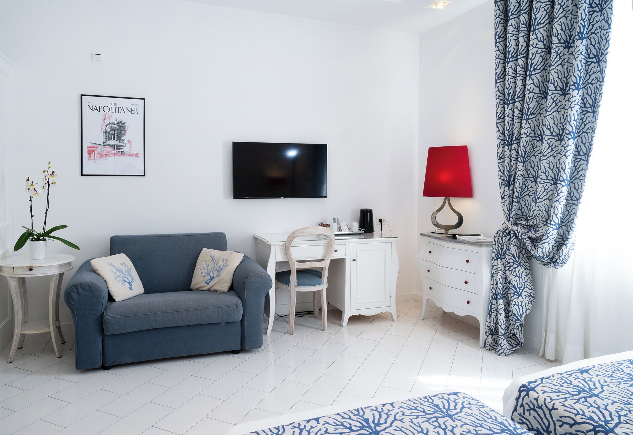 Een moderne kamer met een bank, een bureau, een televisie, een lamp en een kamerkleed met dessin.