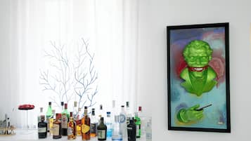 A room with a window, a white cabinet with various bottles, and a framed painting of a green character.