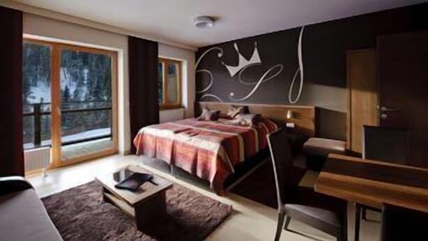 A modern bedroom with a large bed, a desk, and a view of a snowy landscape through the window. - Sissi Park (Oberwölz)