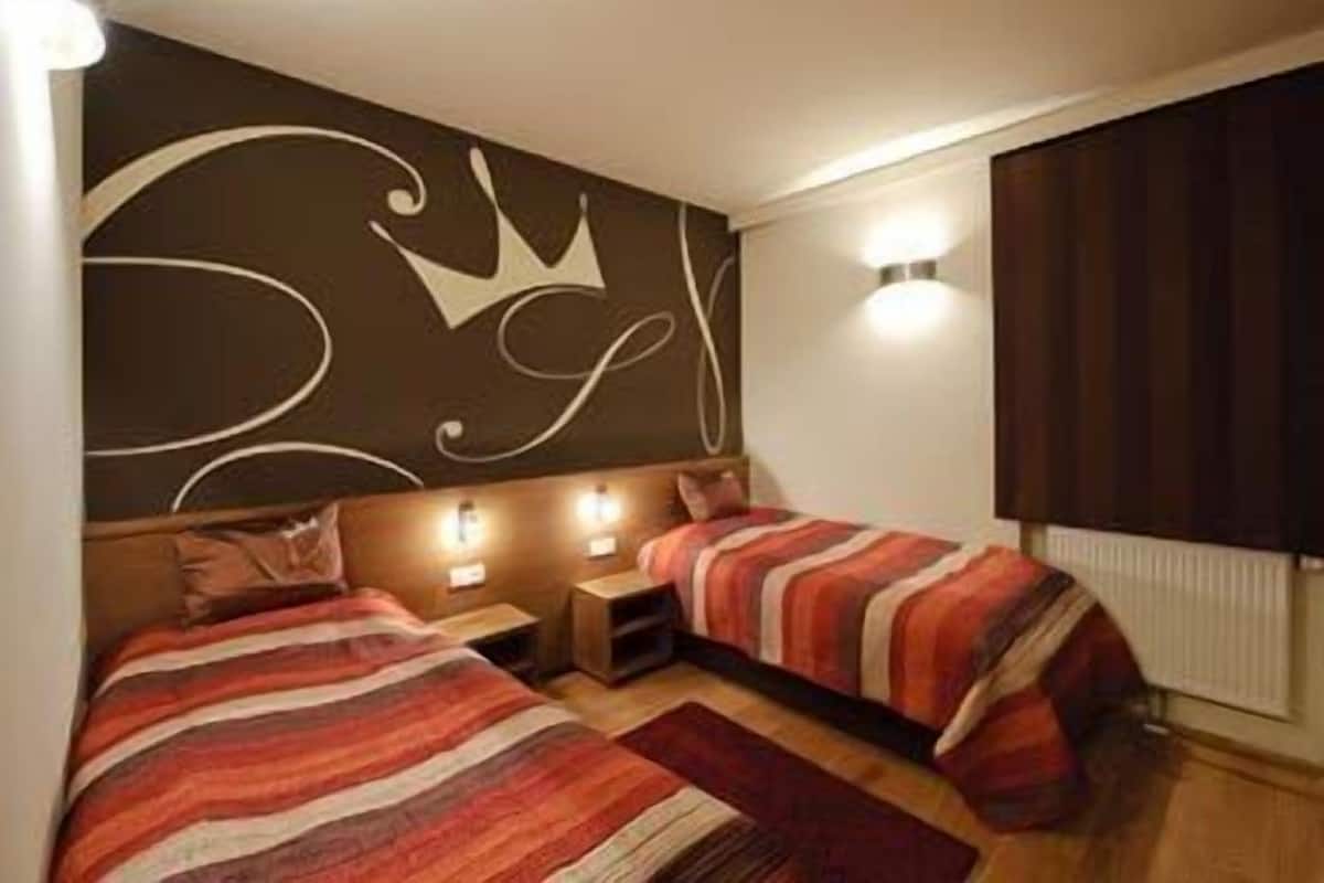Una habitación con dos camas, un adorno en la pared y una ventana con cortinas.