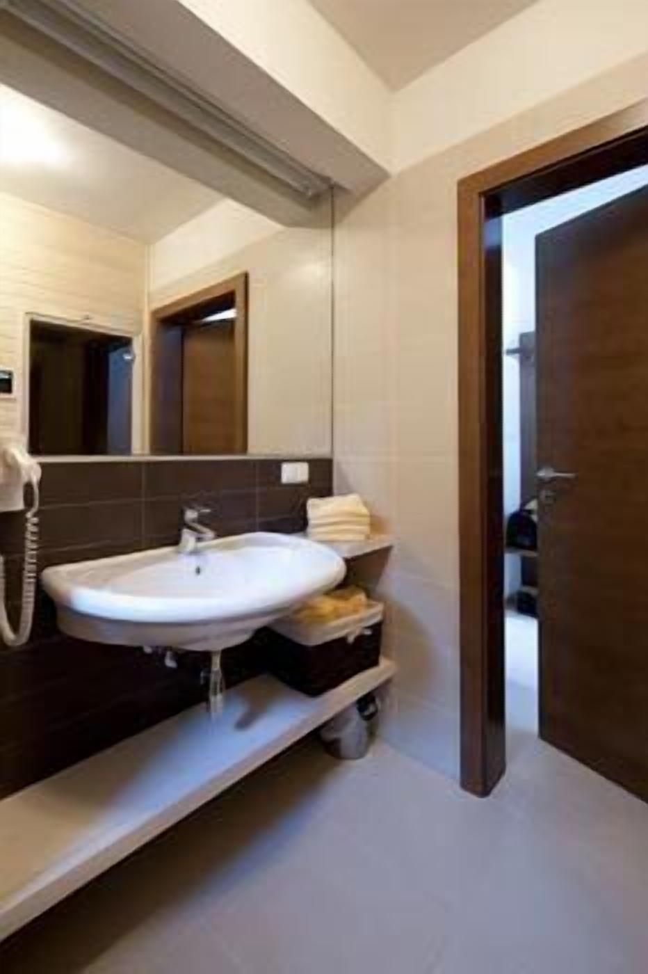 A modern bathroom with a large mirror, a sink, and a toilet.