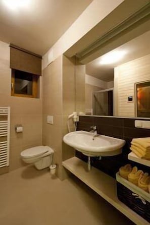 Un baño pequeño con inodoro, lavamanos y espejo.