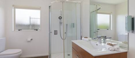A modern bathroom with a glass-enclosed shower, a white sink, and a wooden vanity.