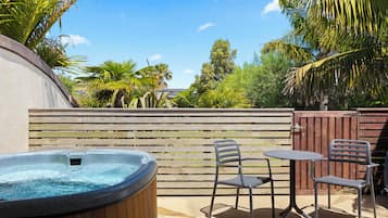 Relax in the serene outdoor patio, featuring a hot tub and comfortable seating for two.