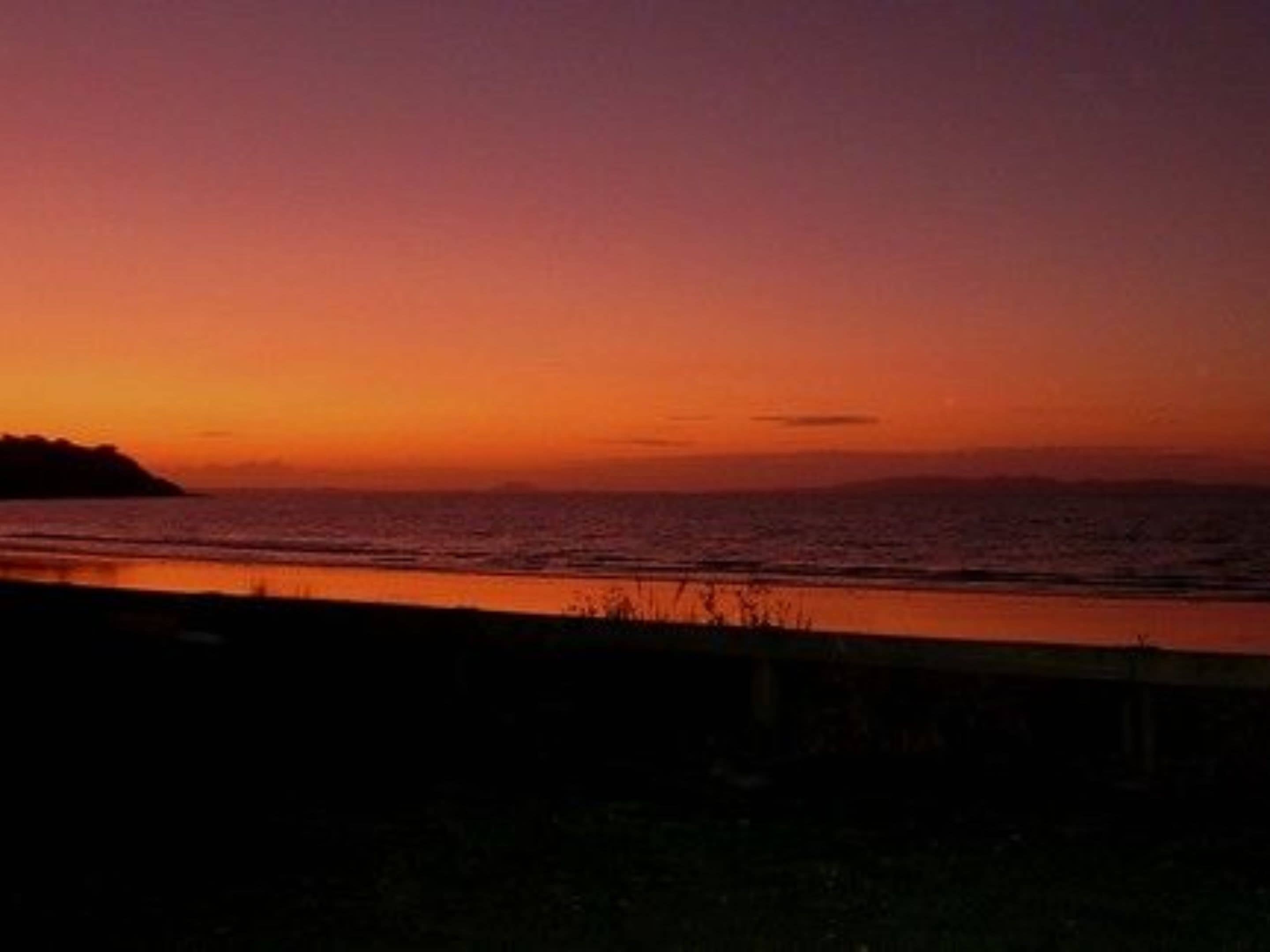 A sunset view over a body of water with a distant landmass.