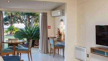 Una habitación con una mesa de comedor, sillas, televisión y vistas al exterior.