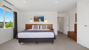 A bedroom with a large bed, a nightstand, a wooden cabinet, and a painting on the wall.